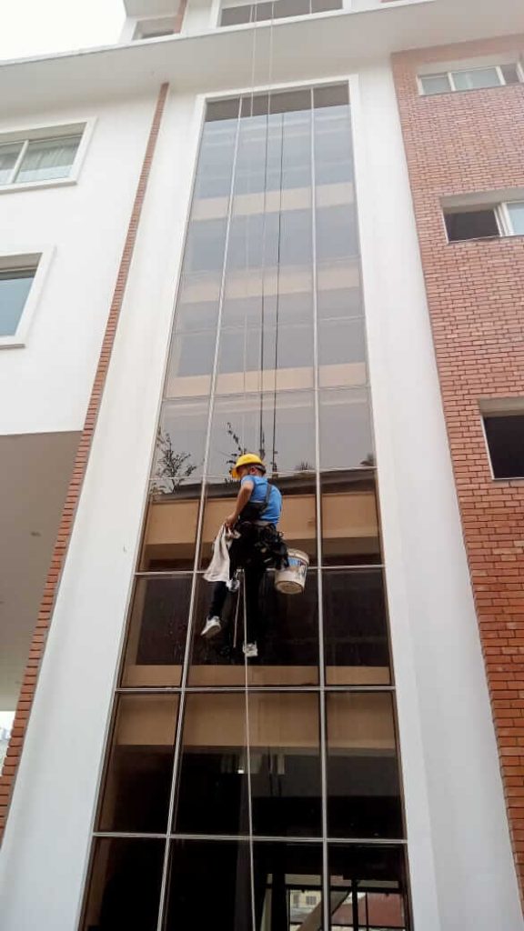 a man cleaning window with the help of harness and rope through glass cleaning service